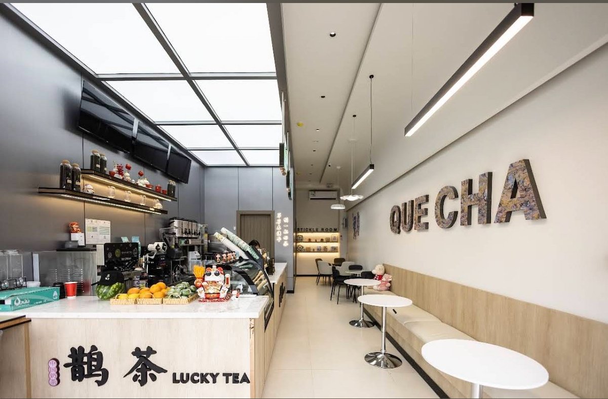 Bright Lucky Tea cafe interior in Riyadh with a service counter, fresh fruit display, and empty round tables in the quiet early morning before the day's rush