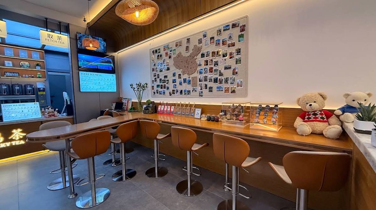 The counter and seating area inside a Lucky Tea bubble tea shop, with drinks on display