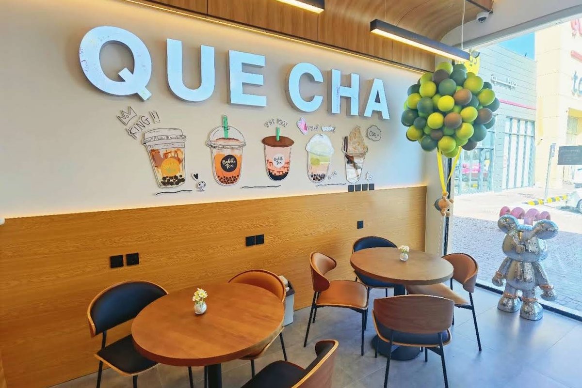 鹊茶门店室内实拍，墙面品牌装饰画搭配气球布置与木质座位区